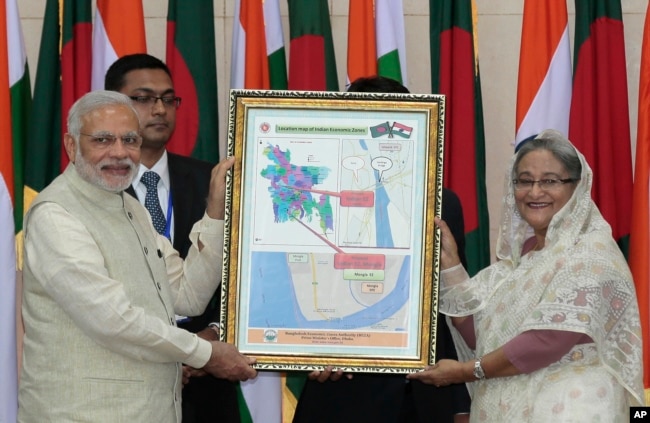 FILE - Bangladesh’s Prime Minister Sheikh Hasina and Indian Prime Minister Narendra Modi hold a location map of Indian Economic Zones during an agreement program in Dhaka, Bangladesh, June 6, 2015.